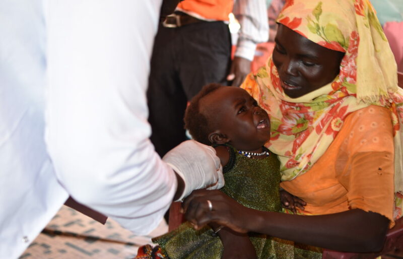 A woman holding a baby girl. The girl is getting vaccination.