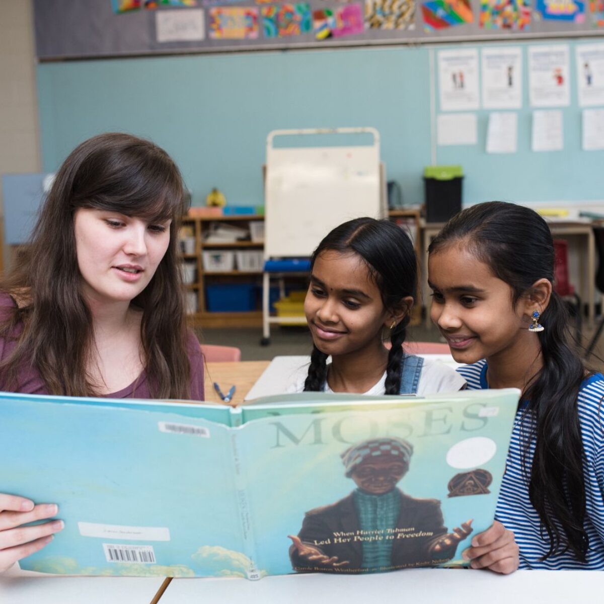 Femme blanche faisant la lecture à deux jeunes filles