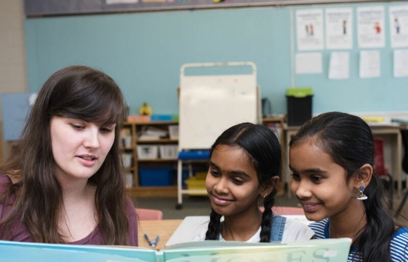 Femme blanche faisant la lecture à deux jeunes filles